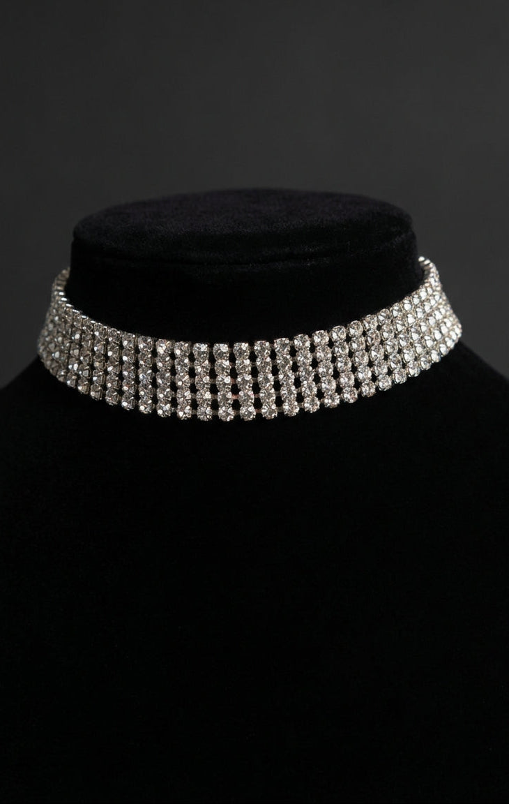 Silver choker necklace on a black mannequin against a dark background