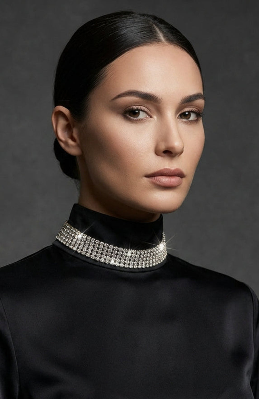 Woman wearing a black high-neck top with a sparkling choker against a dark background