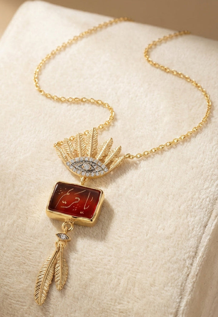 Gold Arabic calligraphy engraved agate pendant necklace on a beige cushion