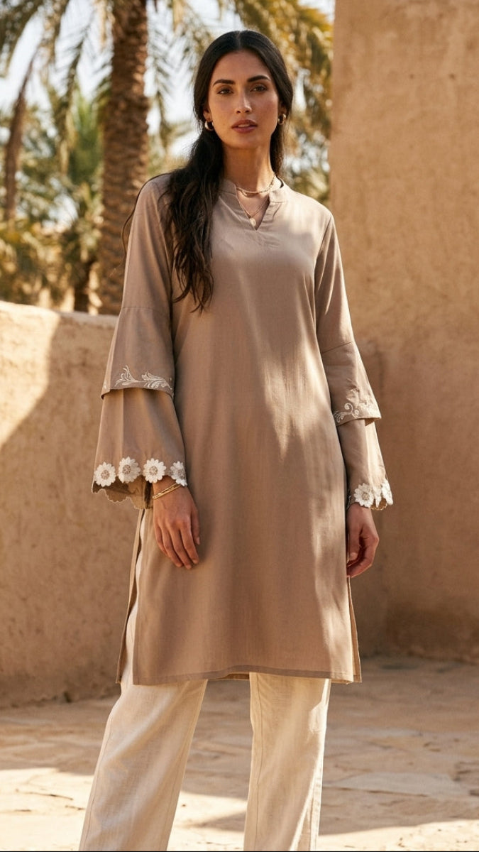 Woman in a beige outfit standing in front of a traditional building with palm trees in the background