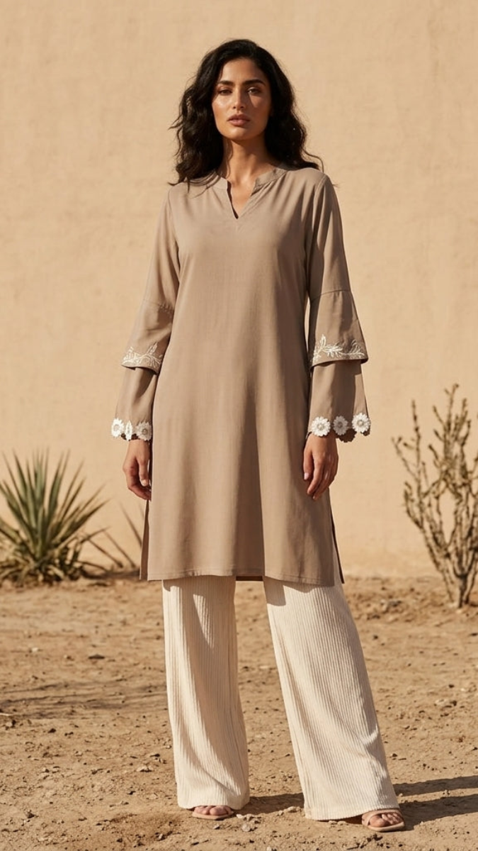 Woman wearing a beige kurta with white pants in a desert setting