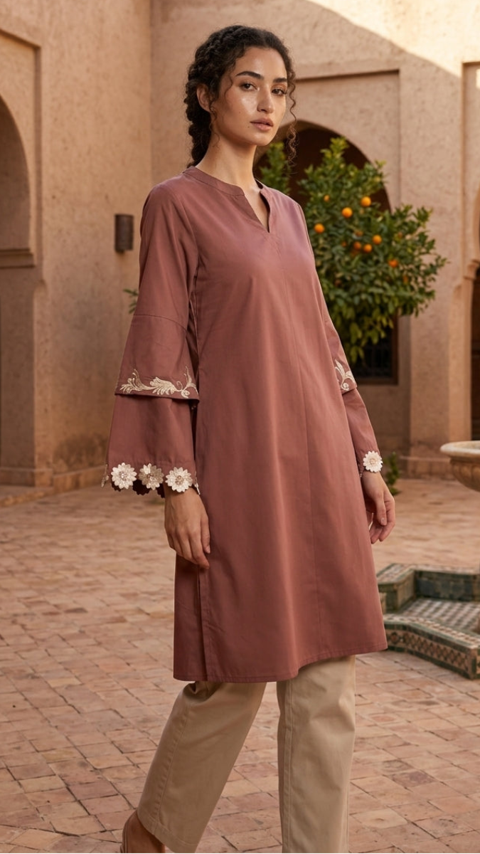 Woman wearing a mauve dress with floral cuffs in an outdoor setting