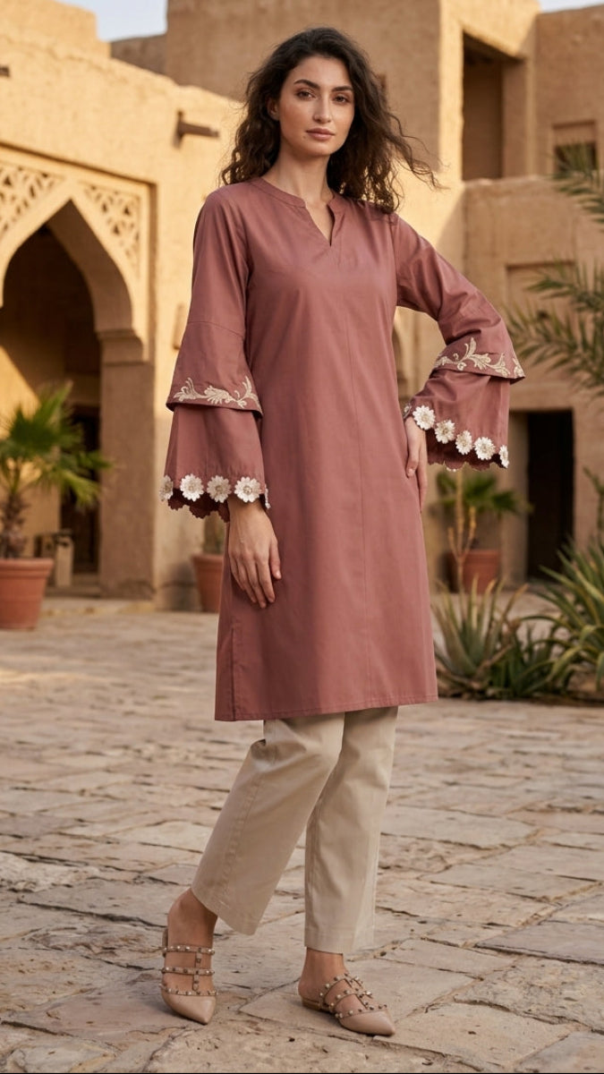 Woman in a pink traditional outfit standing in front of a desert-style building.