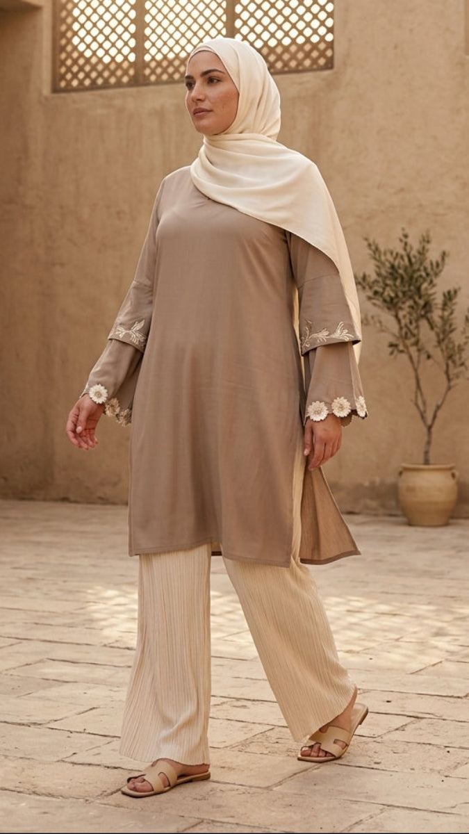Woman in traditional attire walking in a sunlit courtyard with architectural elements.