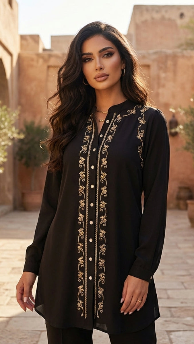 Woman wearing a black embroidered dress in an outdoor setting with architectural elements.