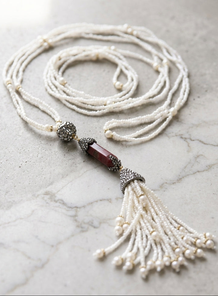 Long beaded necklace with a tassel on a marble surface