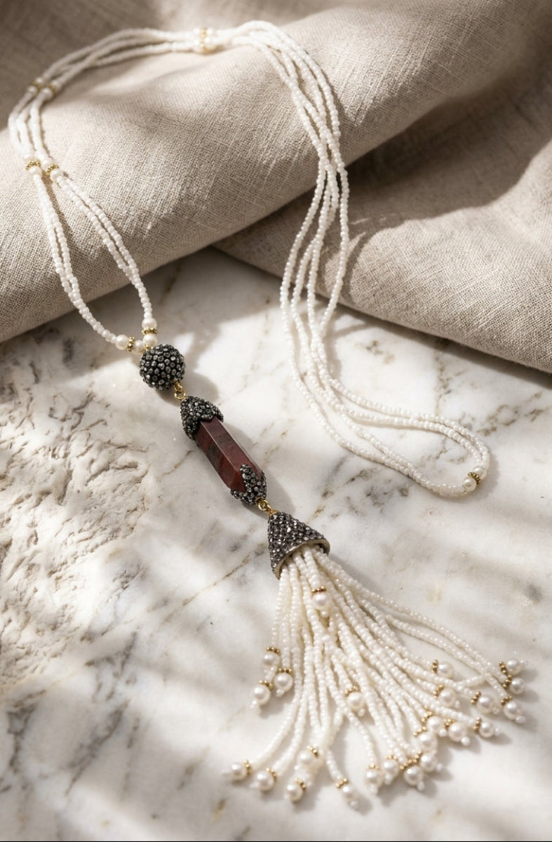 Necklace with beads and tassel on a marble surface