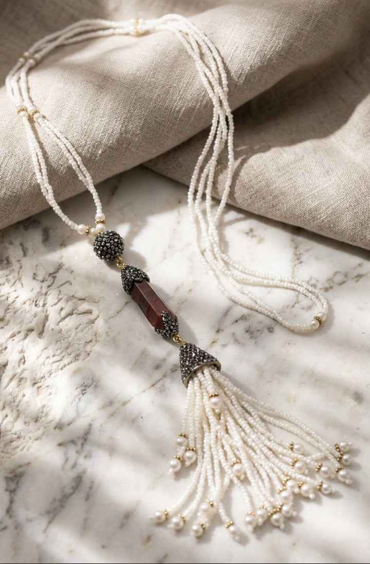 Necklace with beads and tassel on a marble surface