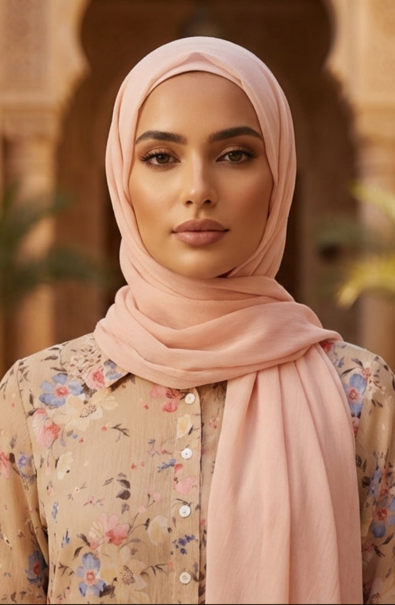 Woman wearing a pink hijab and floral blouse in an ornate architectural setting