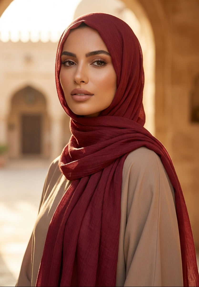 Woman wearing a red hijab and beige outfit in an arched architectural setting