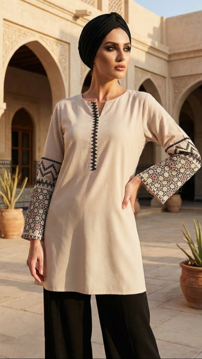Woman wearing a cream-colored top with patterned sleeves in an outdoor setting.
