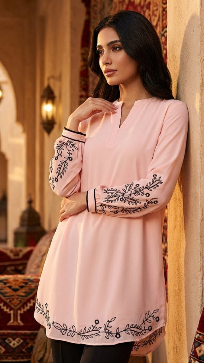 Woman in a pink embroidered dress standing in an ornate room with decorative elements.