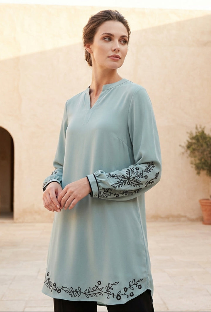 Woman wearing a light blue dress with embroidery in an outdoor setting