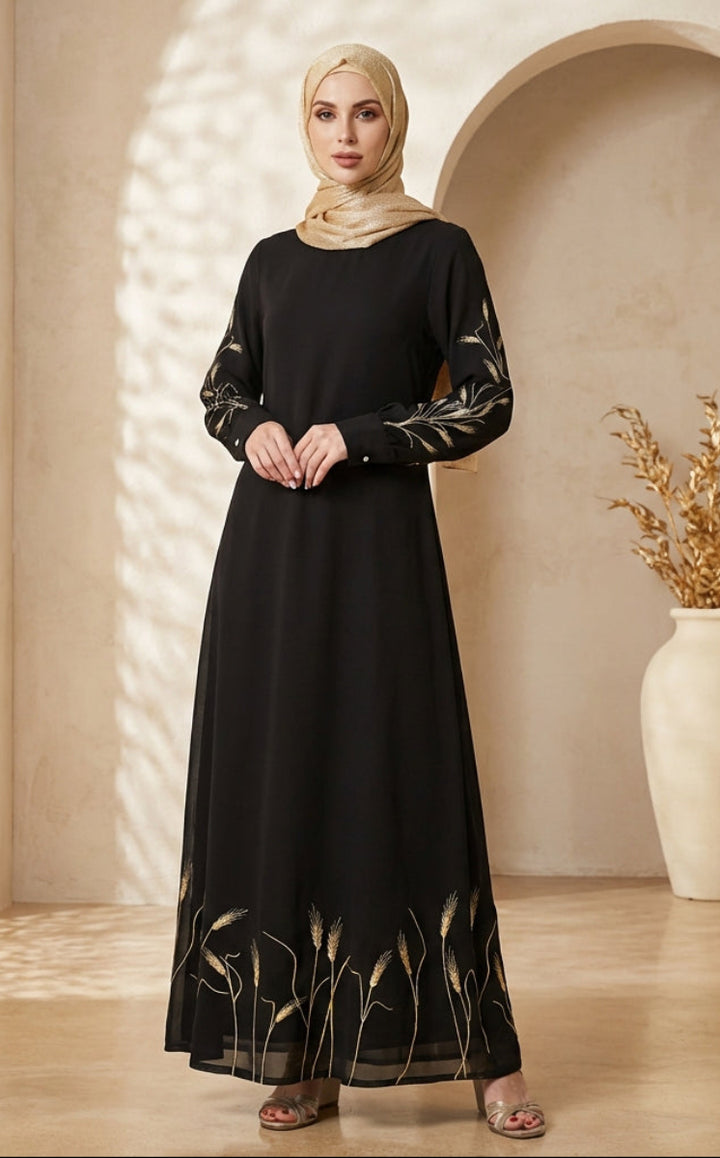 Woman in a black dress with gold detailing standing in a well-lit room with decorative elements.