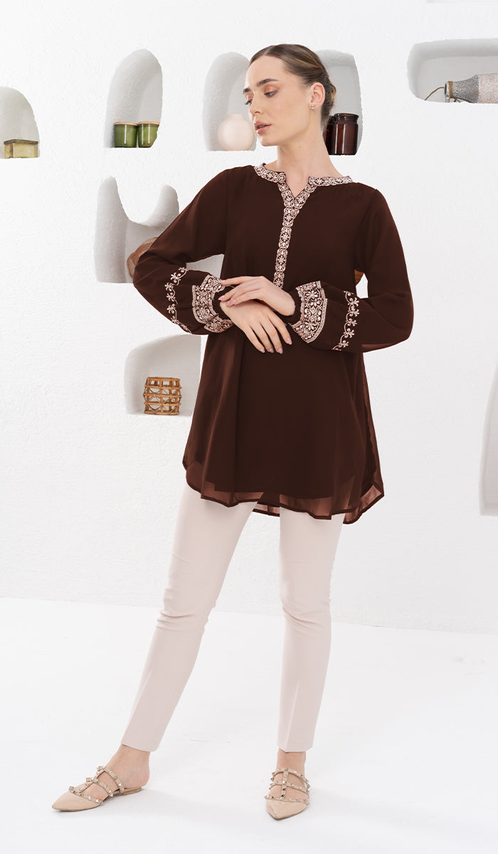 Woman standing in front of bookshelf wearing Amalie tunic in Cocoa. 