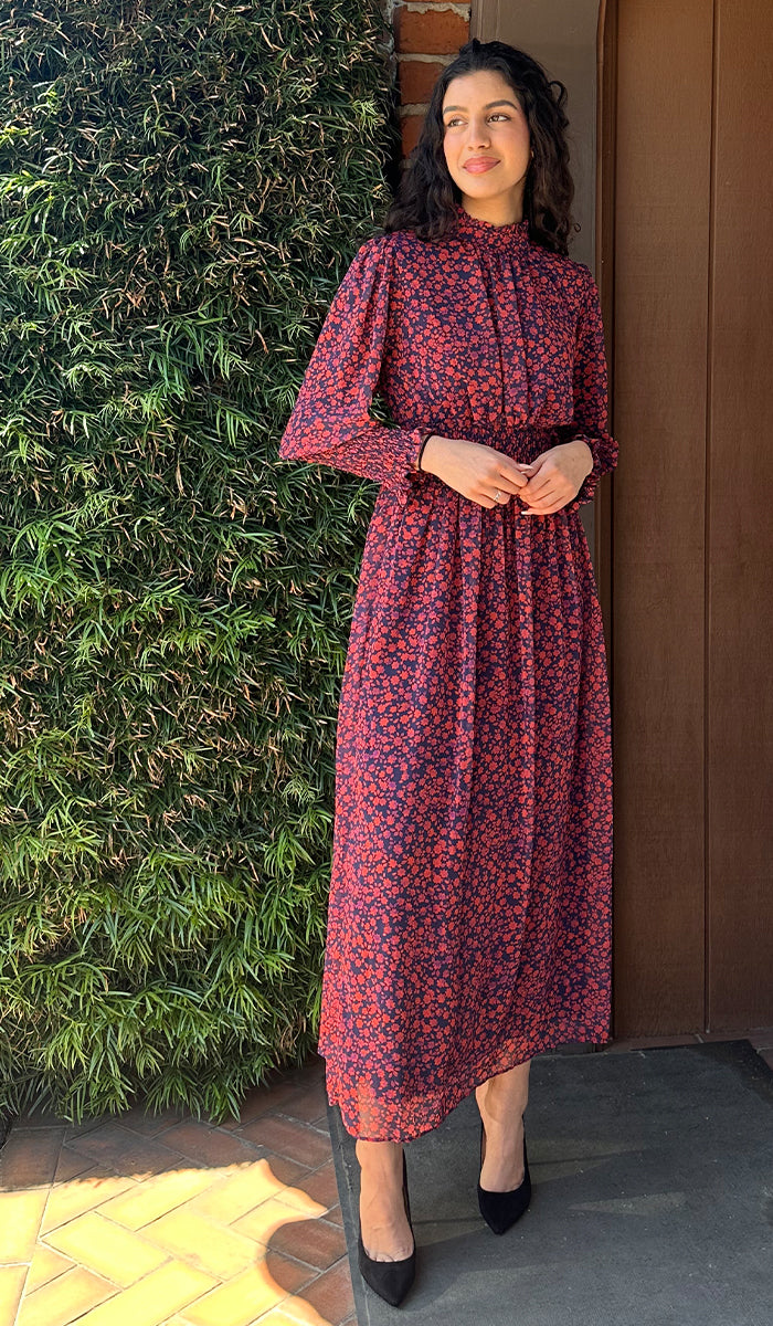 Woman standing near greenery wearing modest Anisa dress. 