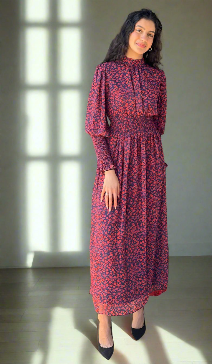 Woman standing near window wearing Anisa floral dress. 
