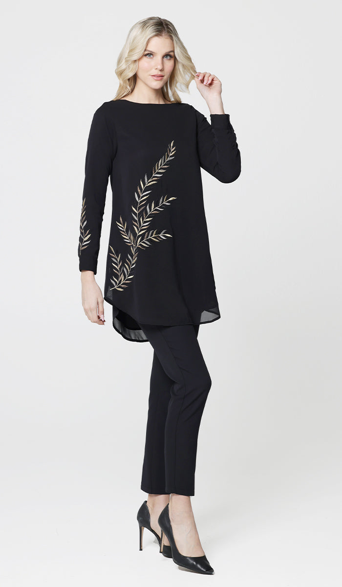 Woman wearing Baraka tunic in Black with black pants and heels. 