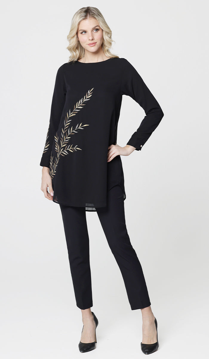 Woman looking to the side wearing Baraka tunic in Black with black pants and heels. 