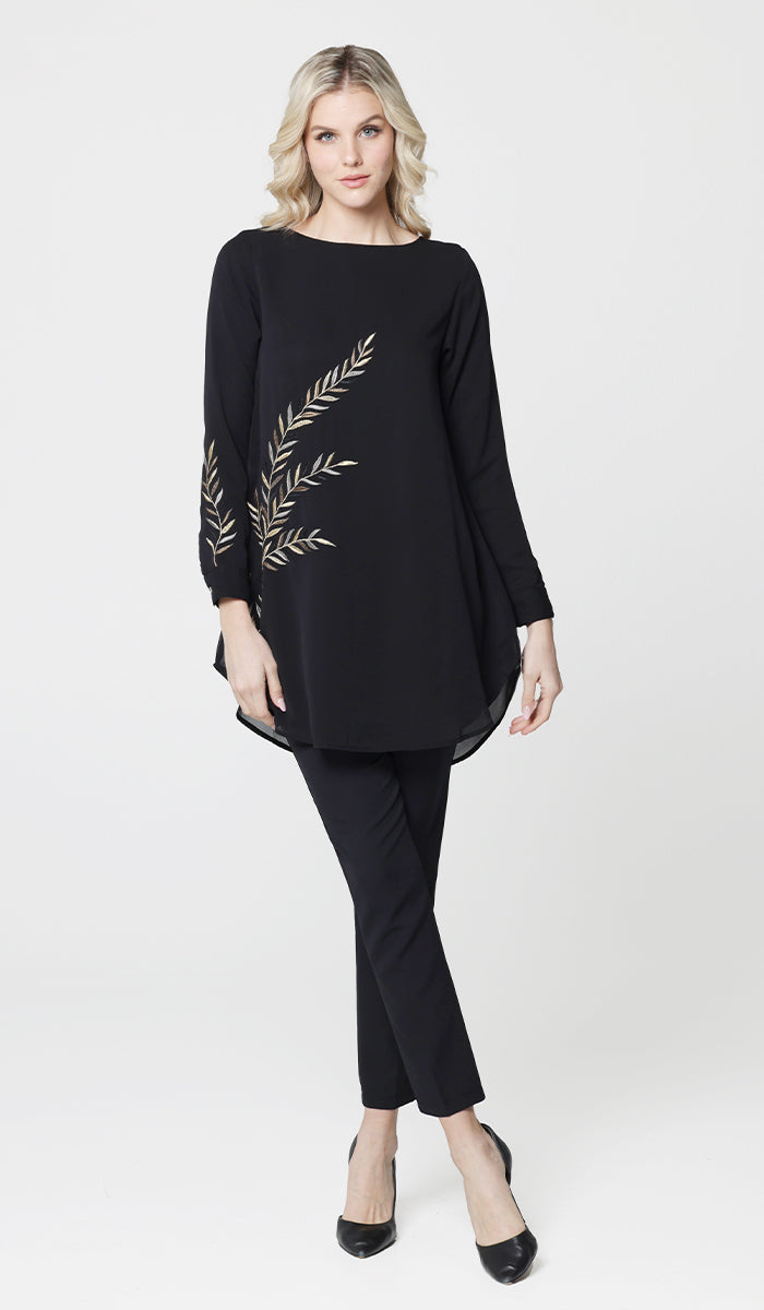 Woman wearing modest embroidered Baraka tunic in Black with black pants and heels. 