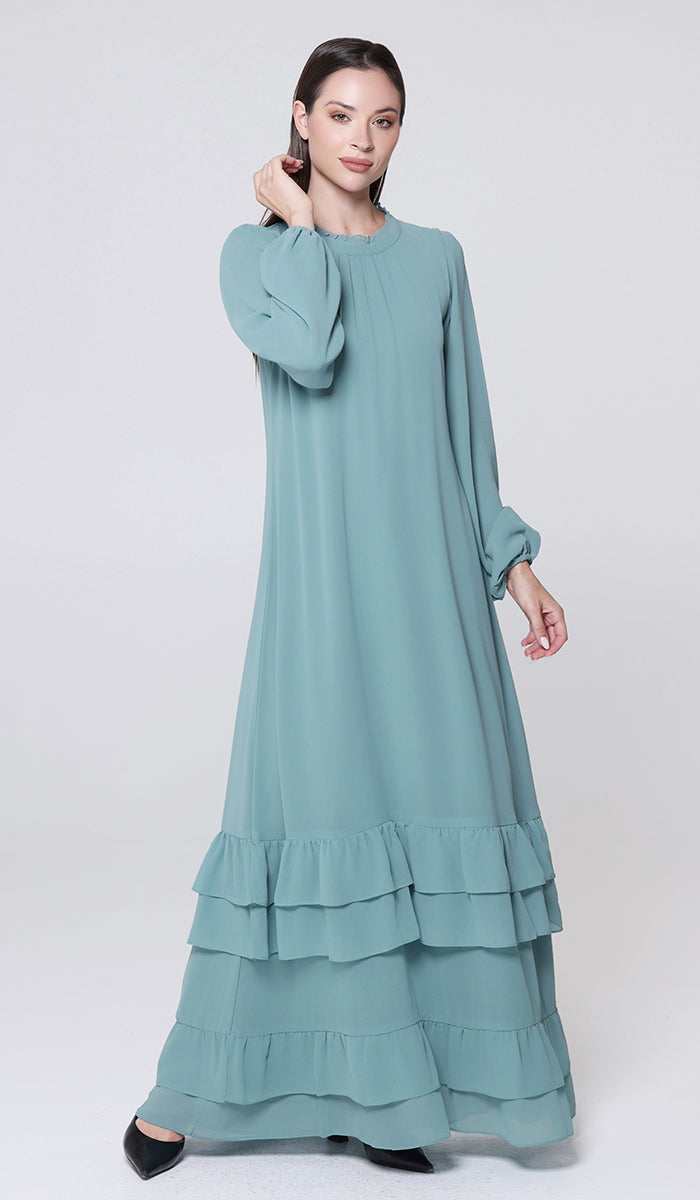 Woman wearing a light blue dress with ruffled layers on a white background