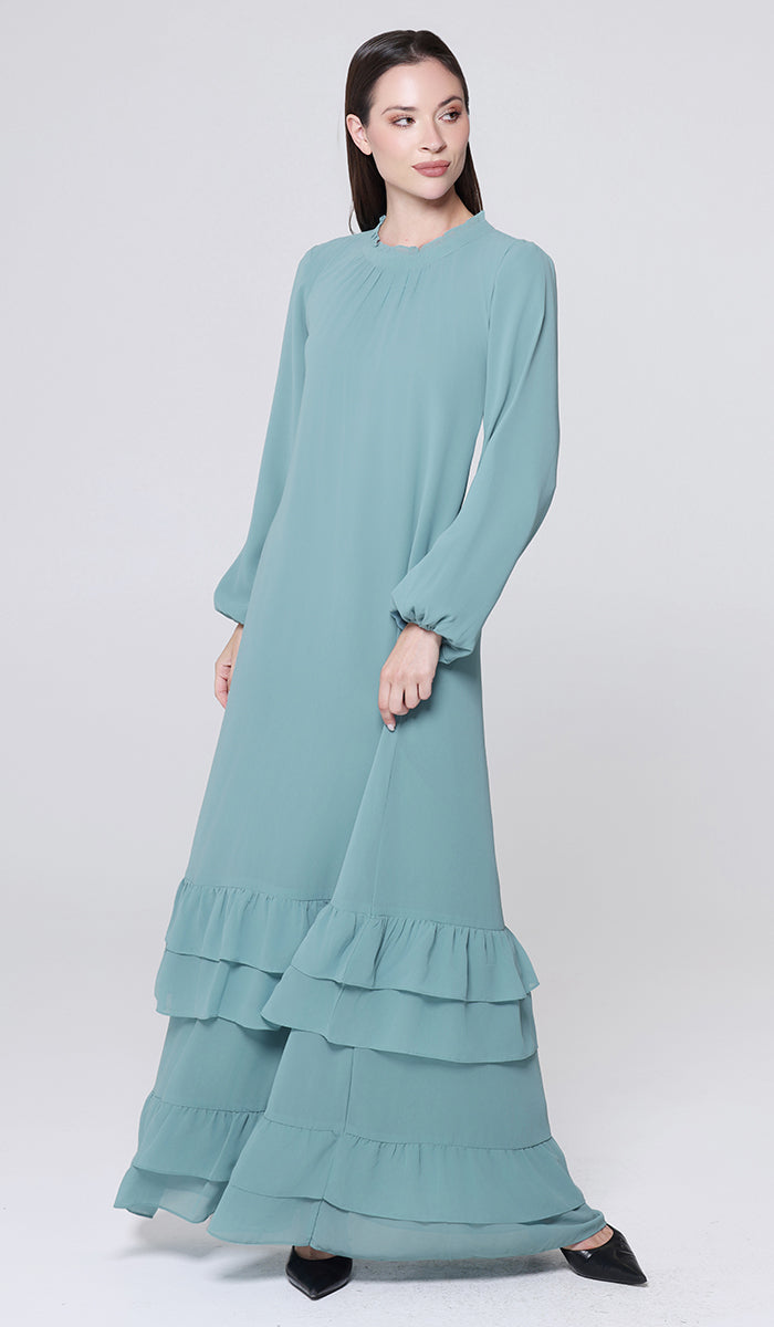 Woman wearing a light blue dress with ruffled layers on a white background