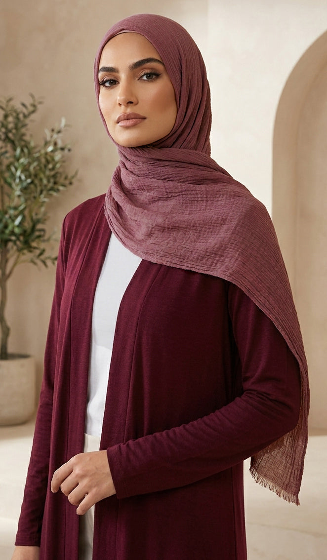 Woman wearing a burgundy hijab and dress in an indoor setting