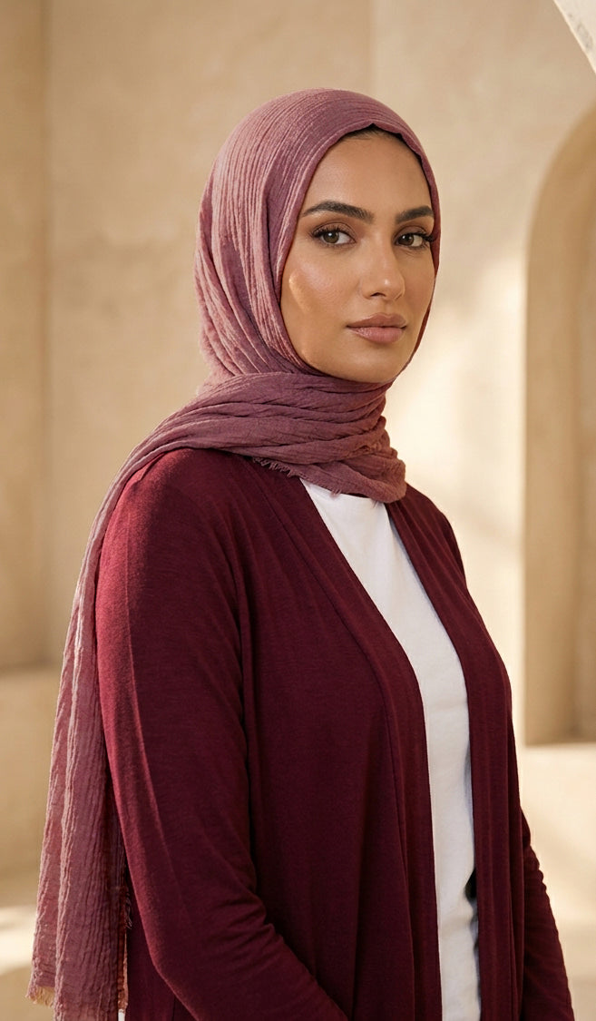Woman wearing a maroon hijab and cardigan in an indoor setting