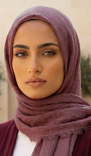 Woman wearing a mauve hijab with a blurred outdoor background