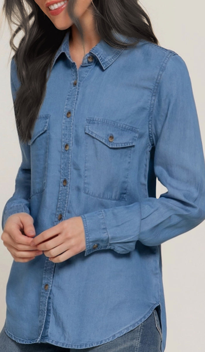 Woman wearing a blue denim shirt against a plain background
