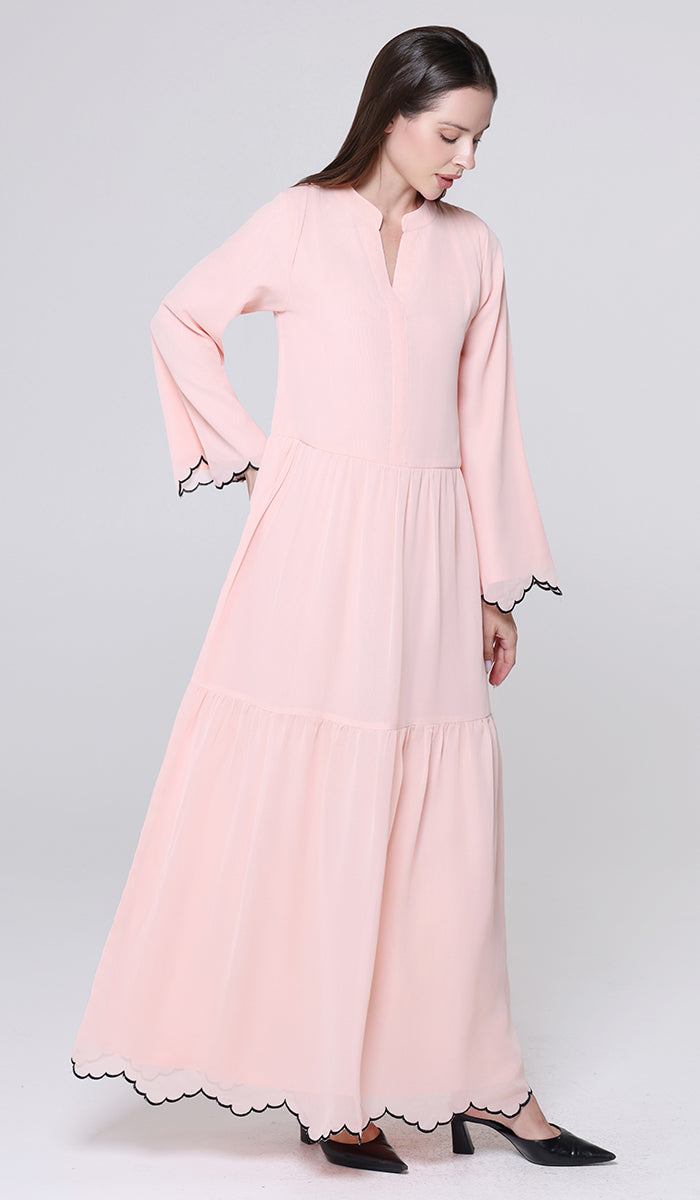 Woman wearing a pink dress with black lace details on a white background