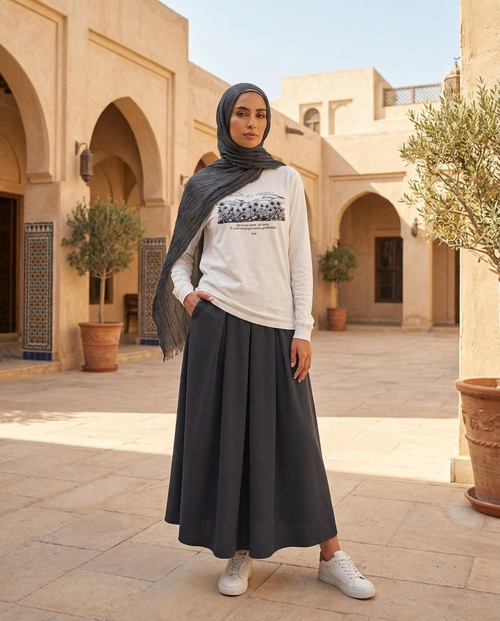 Woman wearing a hijab and outfit in an outdoor setting with architectural elements.