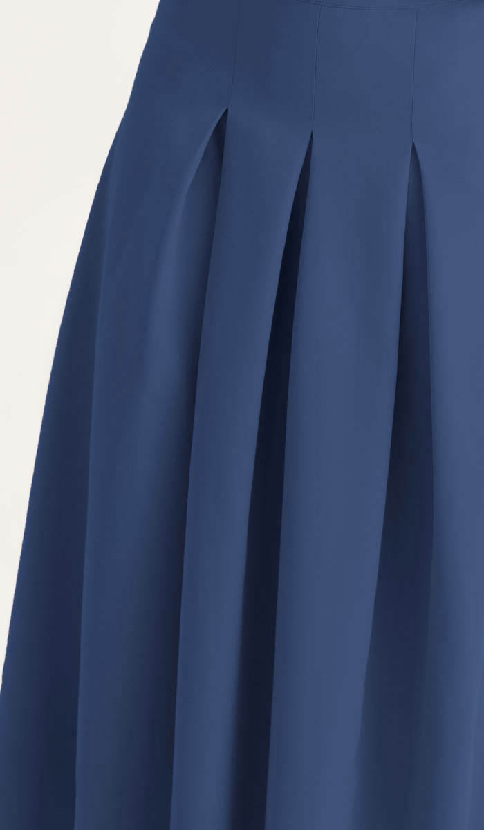 Close-up of a navy blue skirt with pleated details on a light background