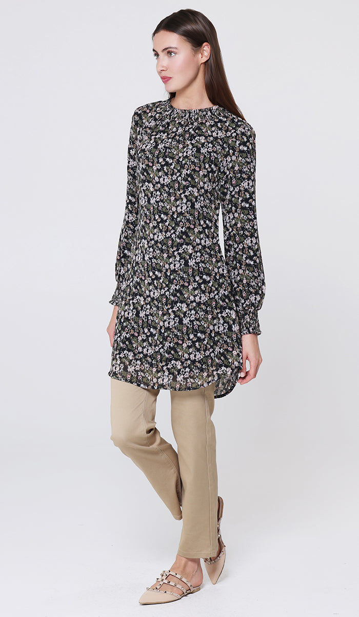Woman wearing a black floral dress with beige pants on a white background