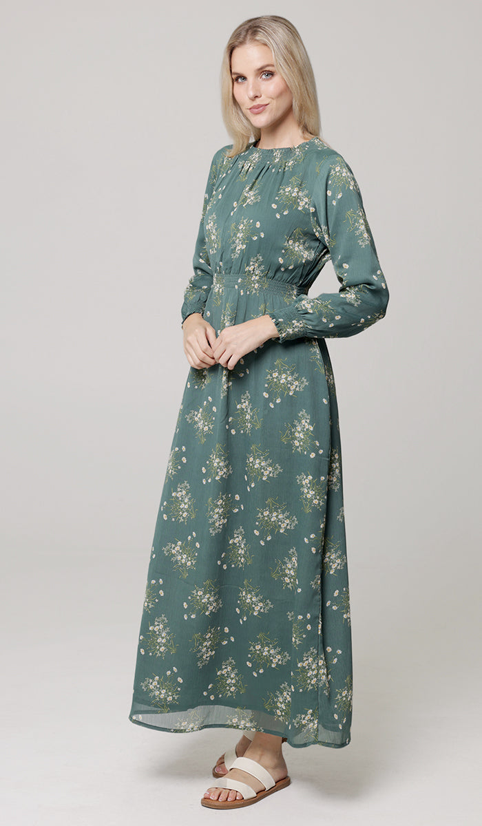 Woman wearing a long green floral dress on a white background