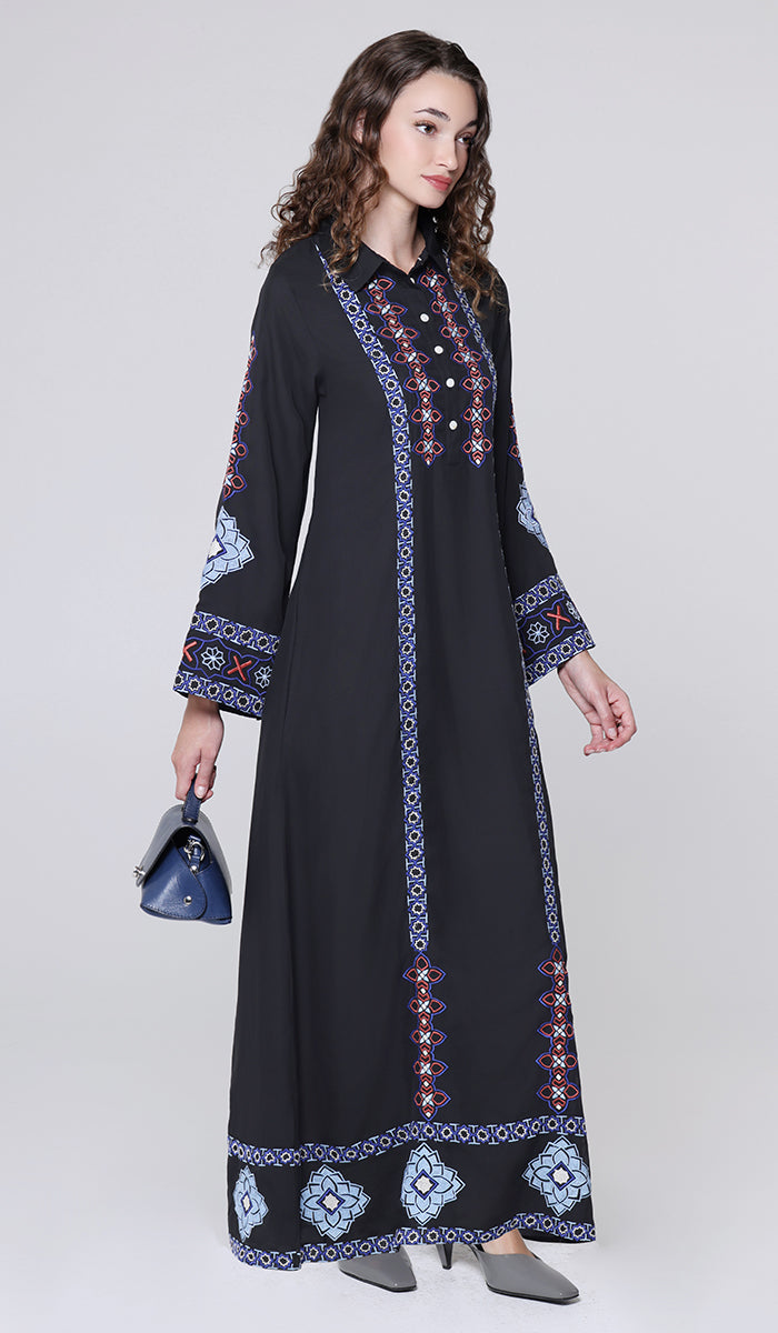 Woman wearing a black dress with colorful embroidery on a white background