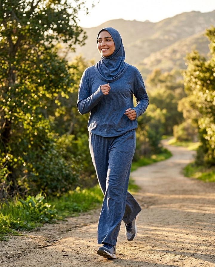 Woman running on a trail in a blue outfit with mountains in the background