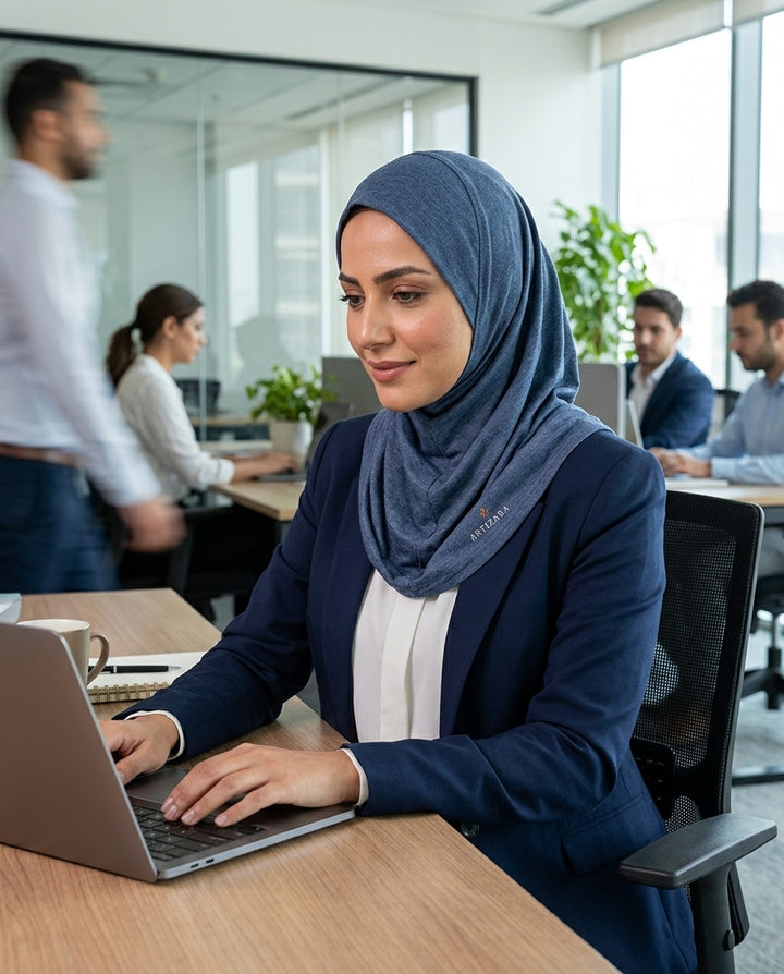 Woman wearing a hijab using a laptop in an office setting
