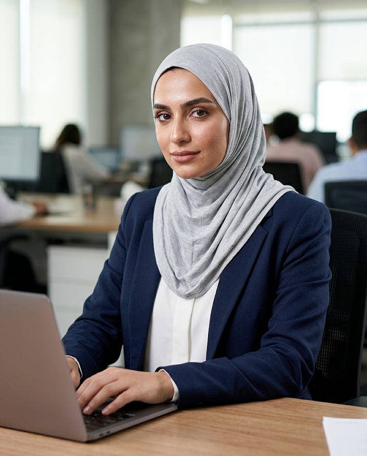 Woman wearing a hijab using a laptop in an office setting