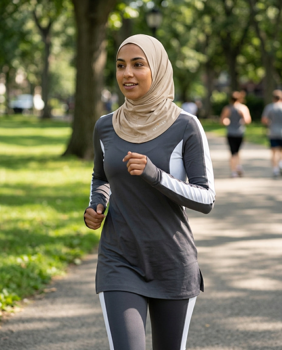 Woman running in a park wearing a hijab and athletic clothing.