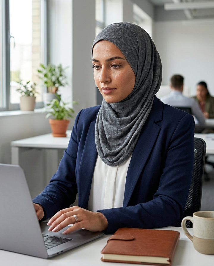 Woman wearing a hijab using a laptop in an office setting