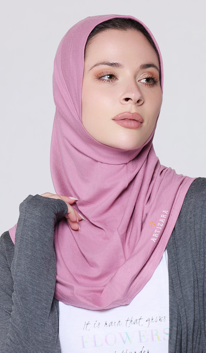Woman wearing a pink hijab with a gray cardigan on a light gray background