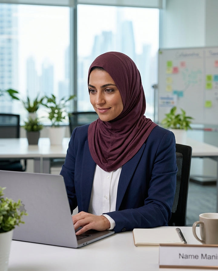 Woman wearing a hijab working on a laptop in an office setting