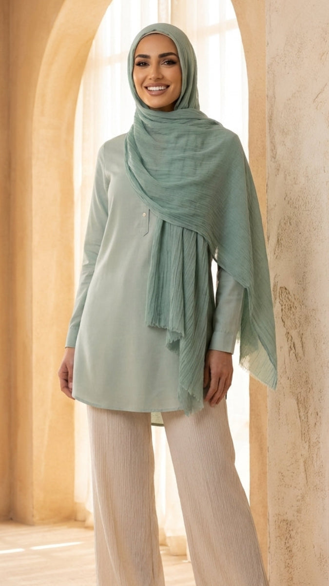 Woman wearing a light green hijab and top in an arched hallway