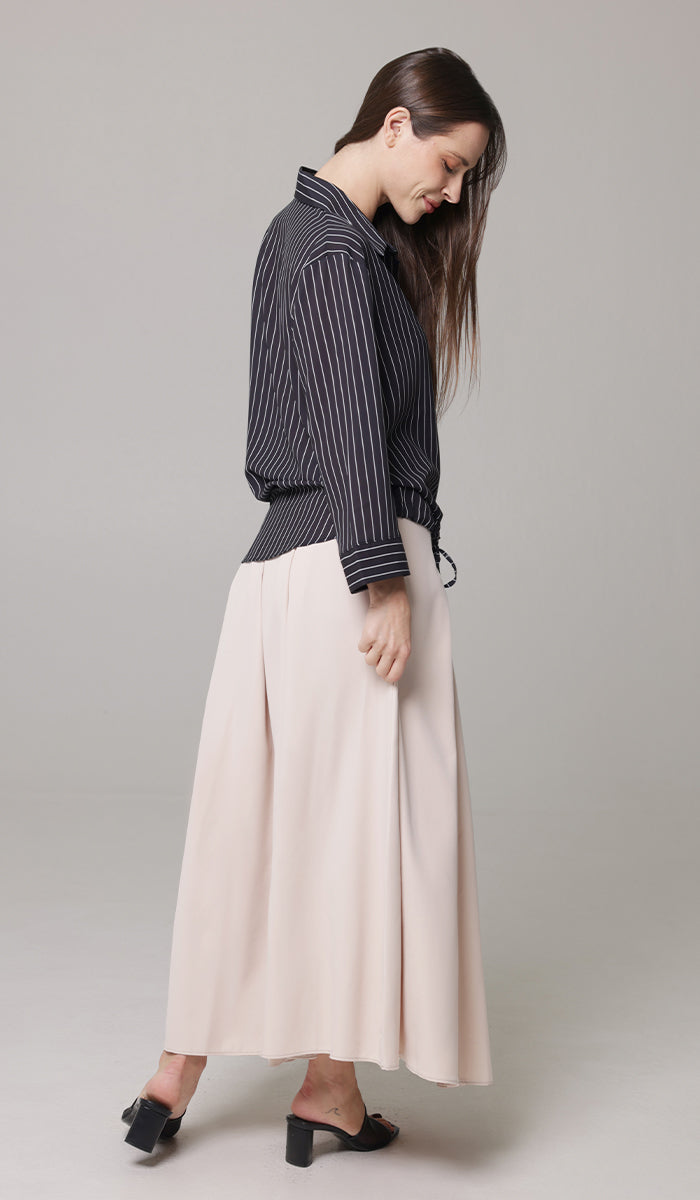 Woman looking down wearing Mia tunic in Blush with Parvin tunic and black heels. 