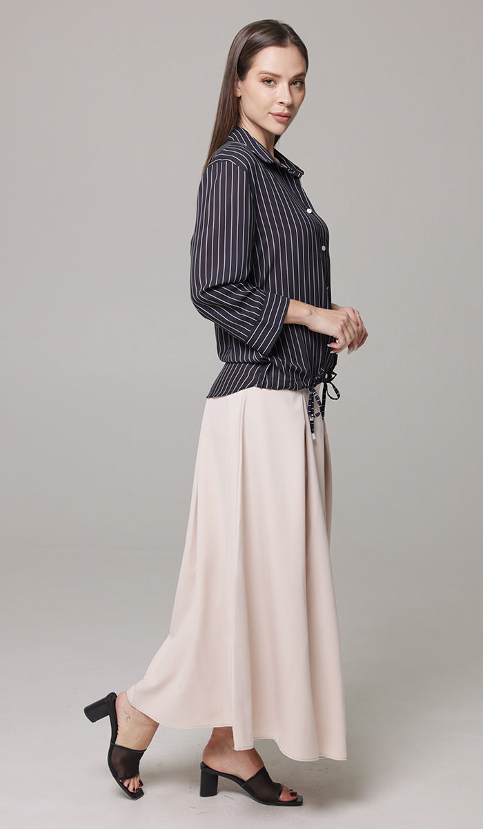 Side view of woman wearing Mia skirt in Blush with Parvin tunic in Black and White and heels. 