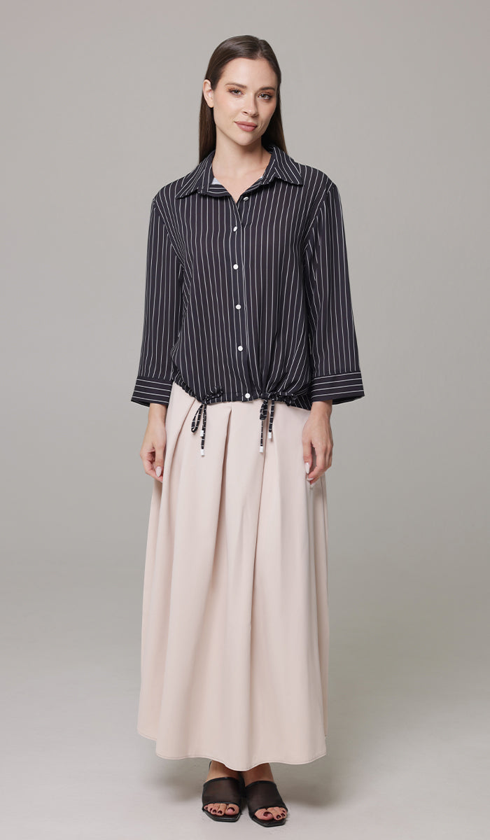 Woman wearing Mia skirt in Blush with Parvin tunic in Black and White with black heels. 