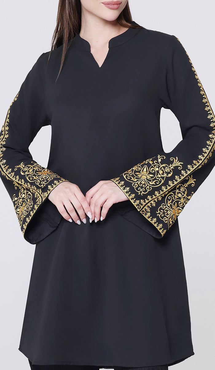 Black dress with gold embroidery on sleeves against a white background