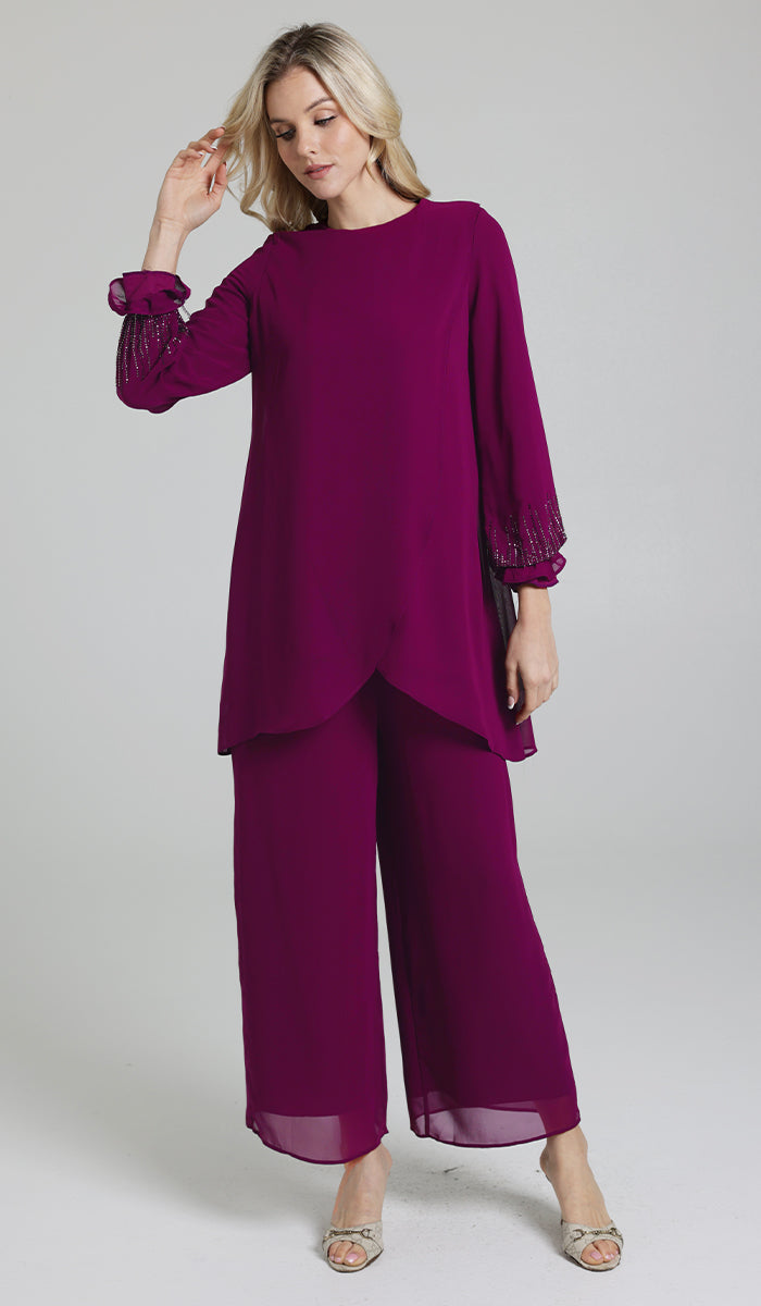 Woman wearing modest Seema tunic in Orchid with pants and heels. 