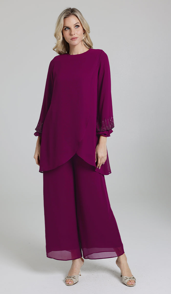 Woman wearing Seema tunic in Orchid with pants and heels. 